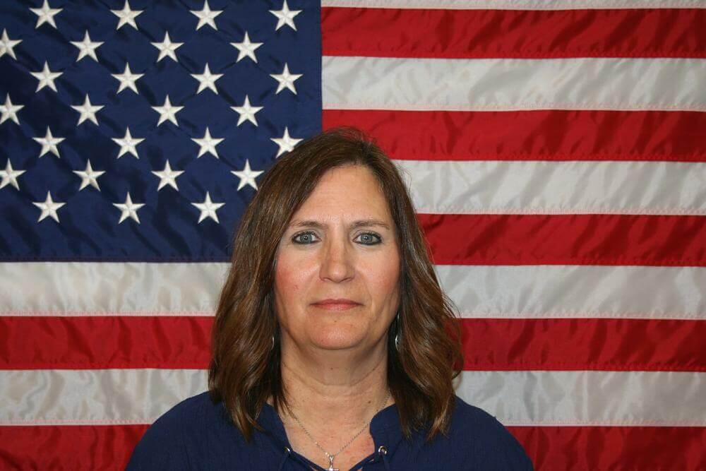 Kathy McDonald standing in front of the flag of the United States of America