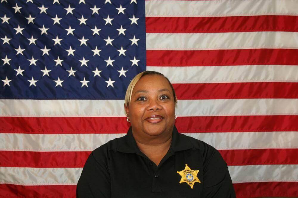 Lt. Edwina Maclin standing in front of the flag of the United States of America.