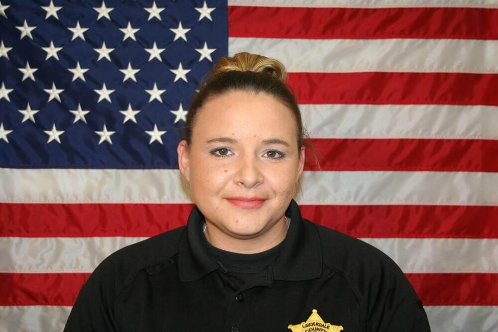 Lt. Whitney Wright standing in front of the flag of the United States of America.