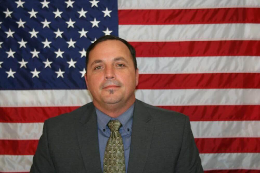 Lt. Karey Williams standing in front of the flag of the United States of America.