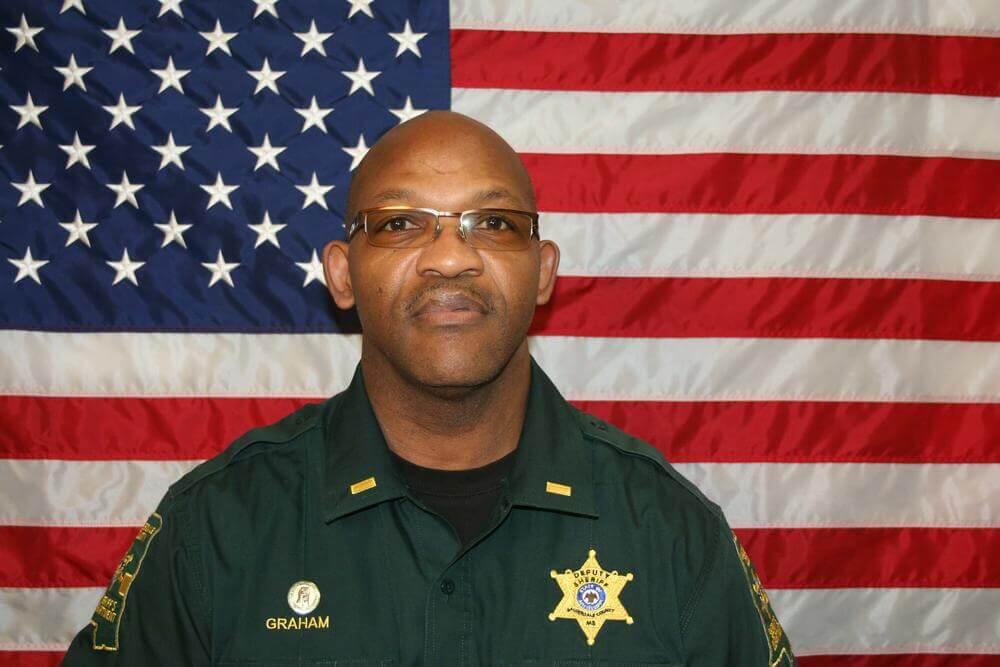 Lt. Willie Graham standing in front of the flag of the United States of America.