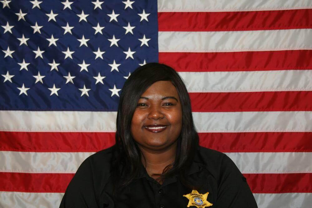 Sgt. LaToya Bennett standing in front of the flag of the United States of America.
