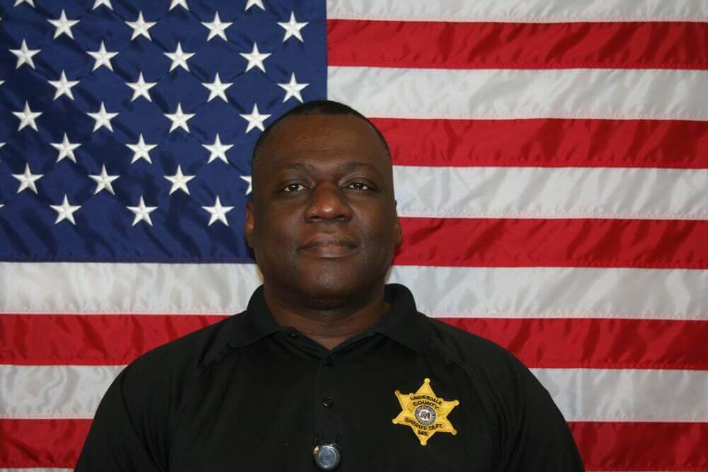 Sgt. Tommy Creer standing in front of the flag of the United States of America.