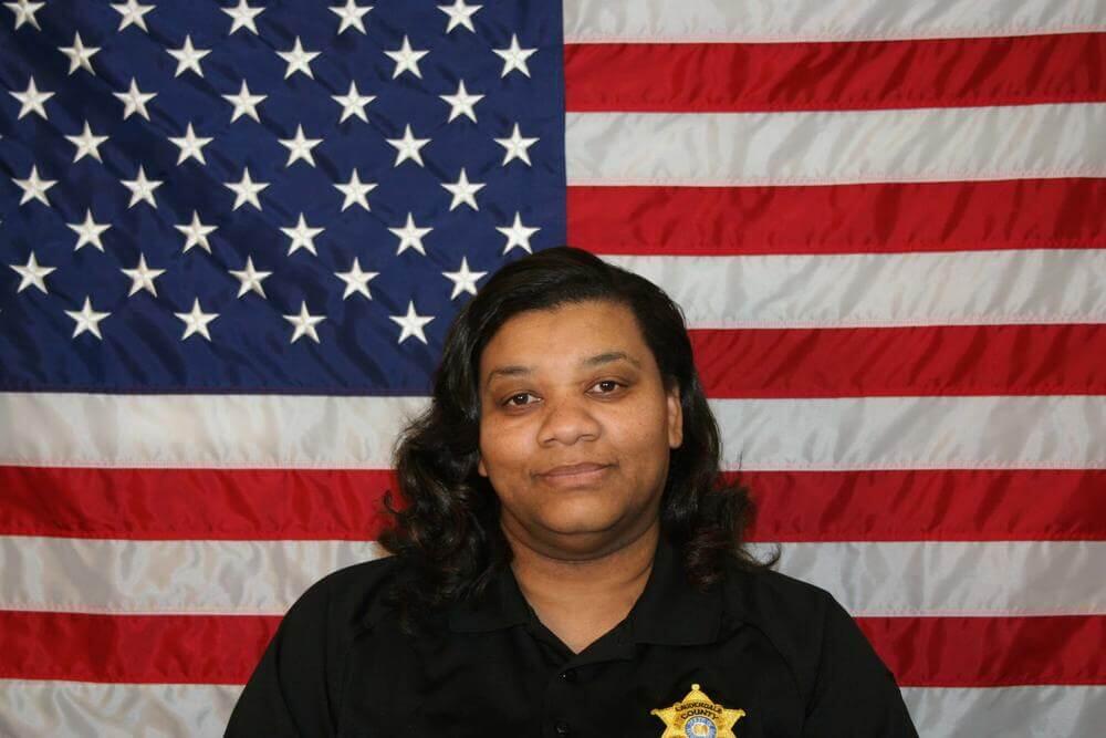 Cheryl Porter standing in front of the flag of the United States of America.