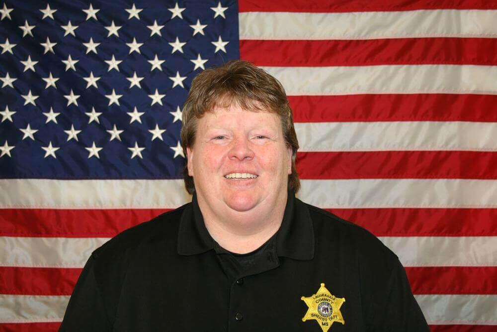 Major Melissa McCarter standing in front of the flag of the United States of America.