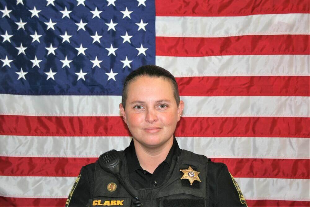 Kara Clark standing in front of the flag of the United States of America.