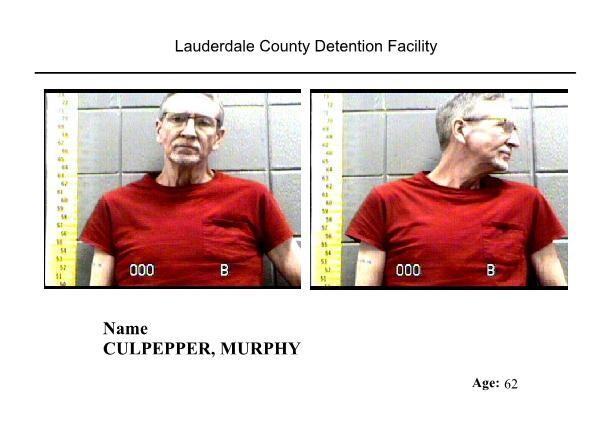 White male with gray hair and glasses red shirt taking mugshot after arrest