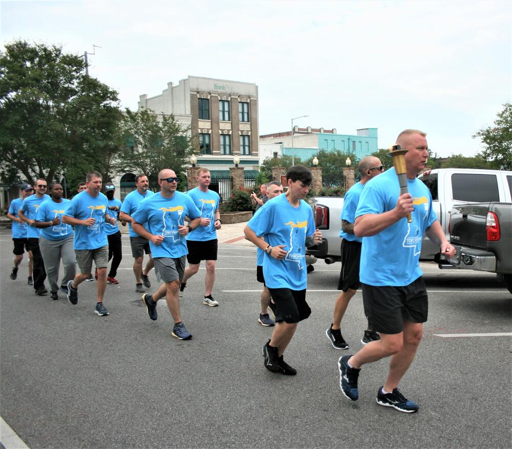 Black and White Female and Male Law Enforcement Officers dressed in light blue Special Olymplics Tshirts running for the benefit of Special Olympics.