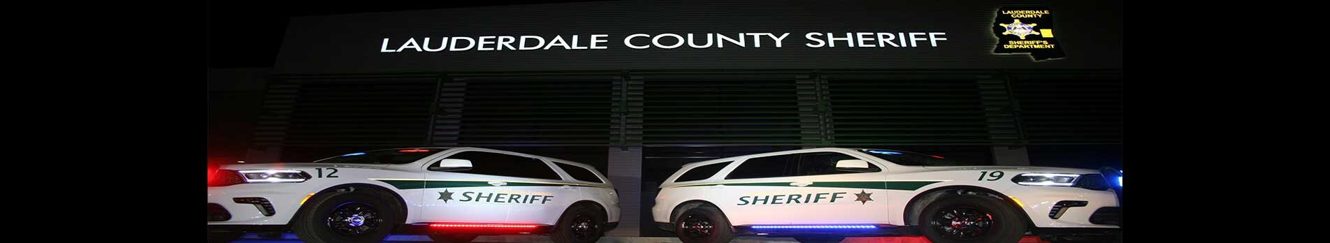 Two Lauderdale County Sheriff's Office patrol cars in front of the Sheriff's Office at night.