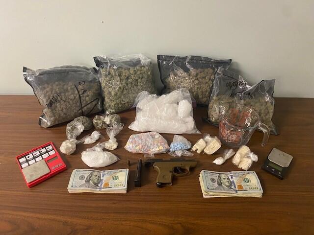 ziplock bags of marijuana, ice, blue pills, crack cocaine a green handgun and 2 stacks of $100 dollar bills.
